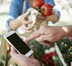 Mann mit Handy am Gemüsestand